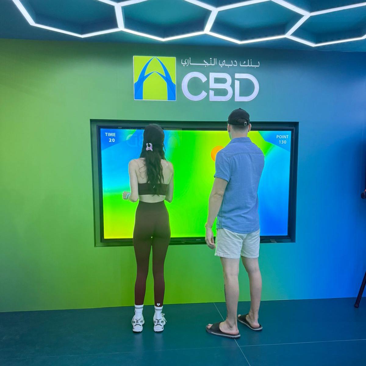 Interactive multi-level touch screen game rental at Dubai 30x30 event, showing guests engaged in a gamified fitness and financial literacy challenge.